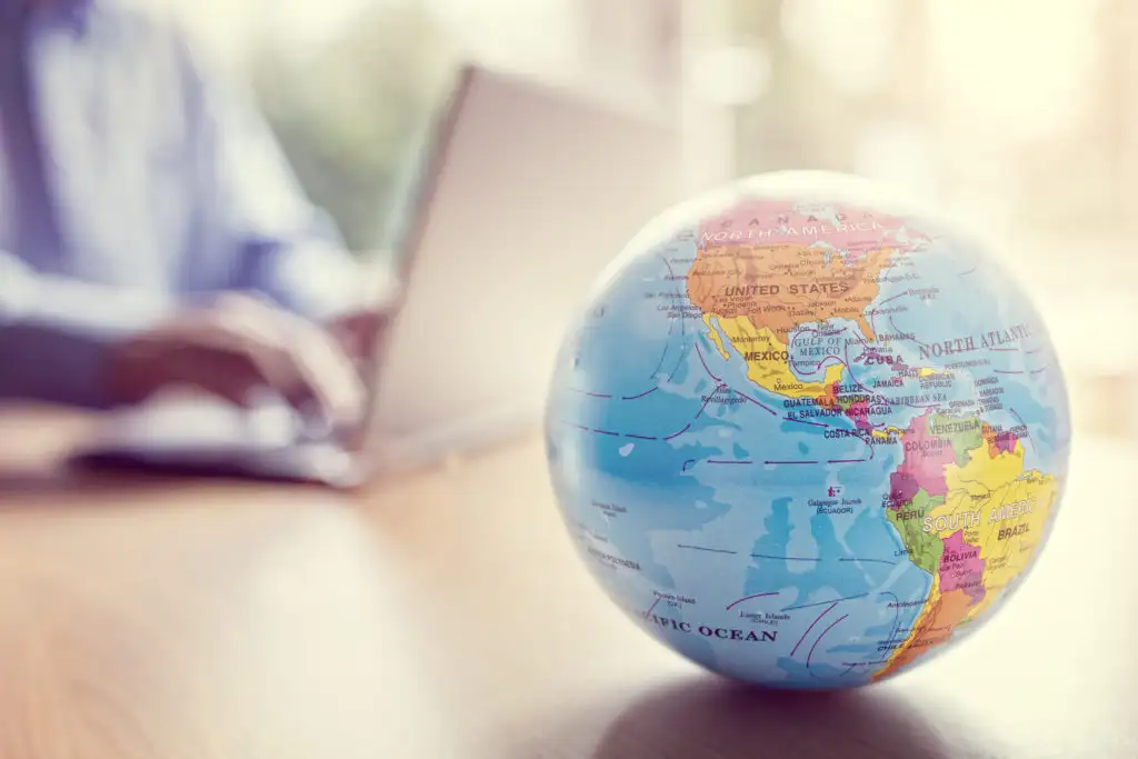 Globe in foreground with laptop out of focus in background