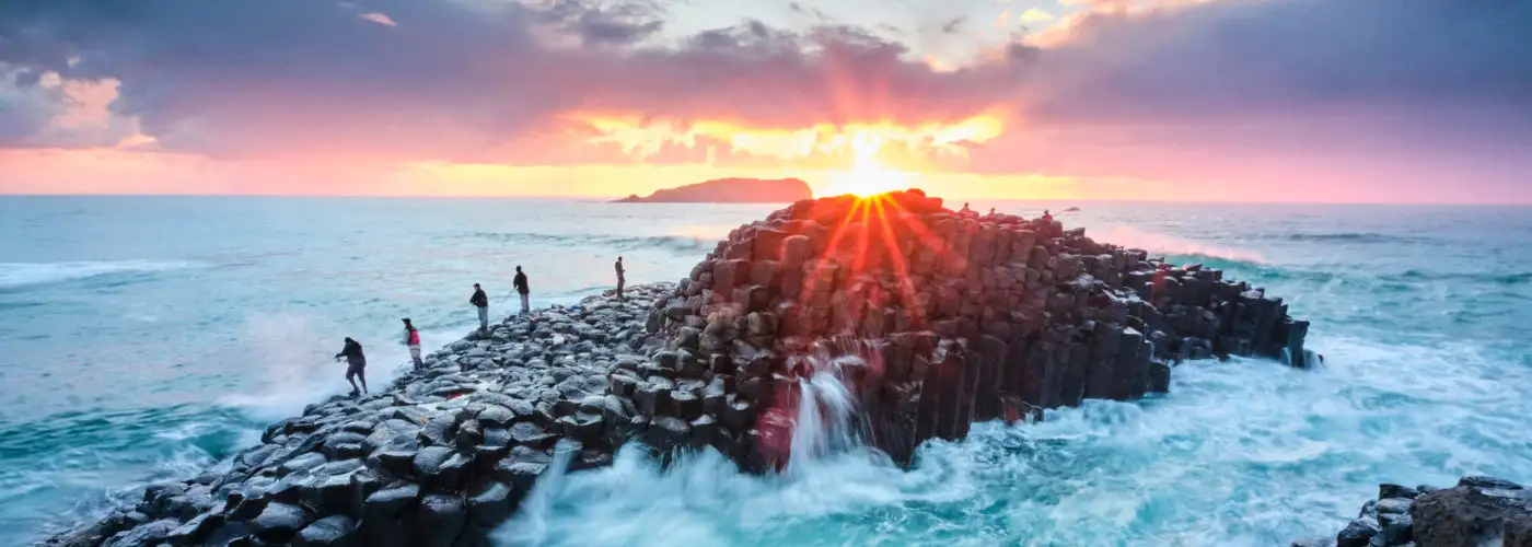 Fisherman on Giant's Causeway at sunrise in Ireland
