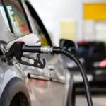 Close up of a gas pump attached to a car as it refuels at a gas station