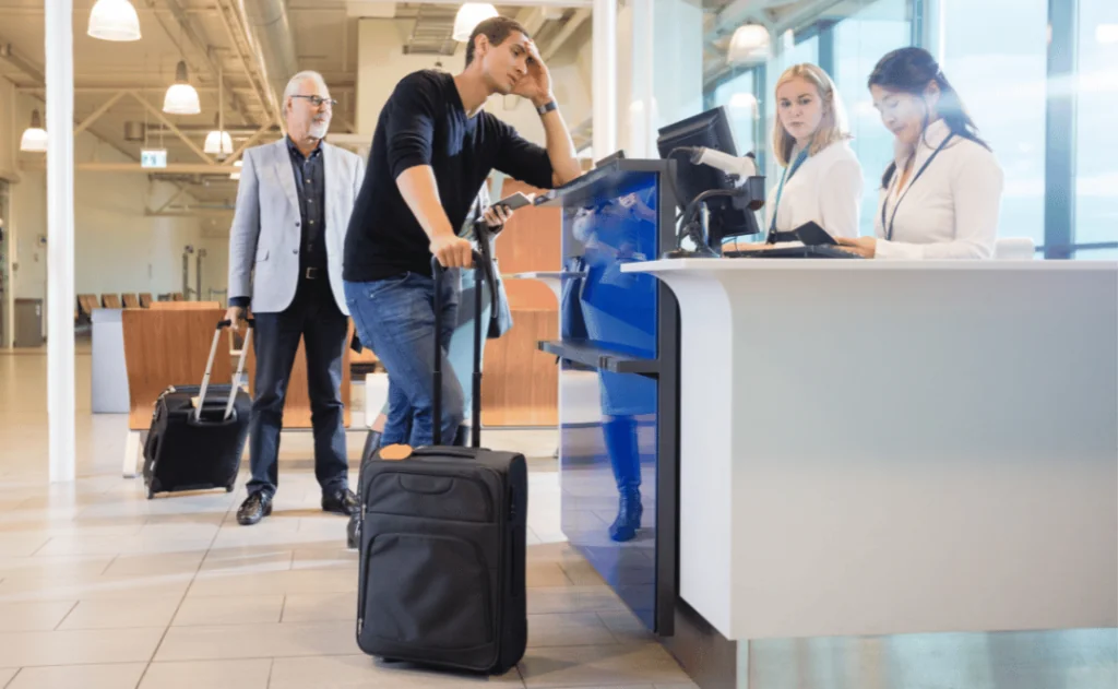 Staff Checking Male Passenger At Counter In Airport