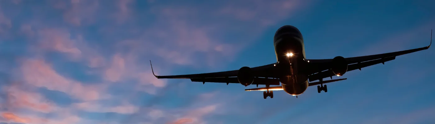 Landing airplane at colorful sunrise with with beams of sun lights. Concept of transport, weather, travel and happy vacation