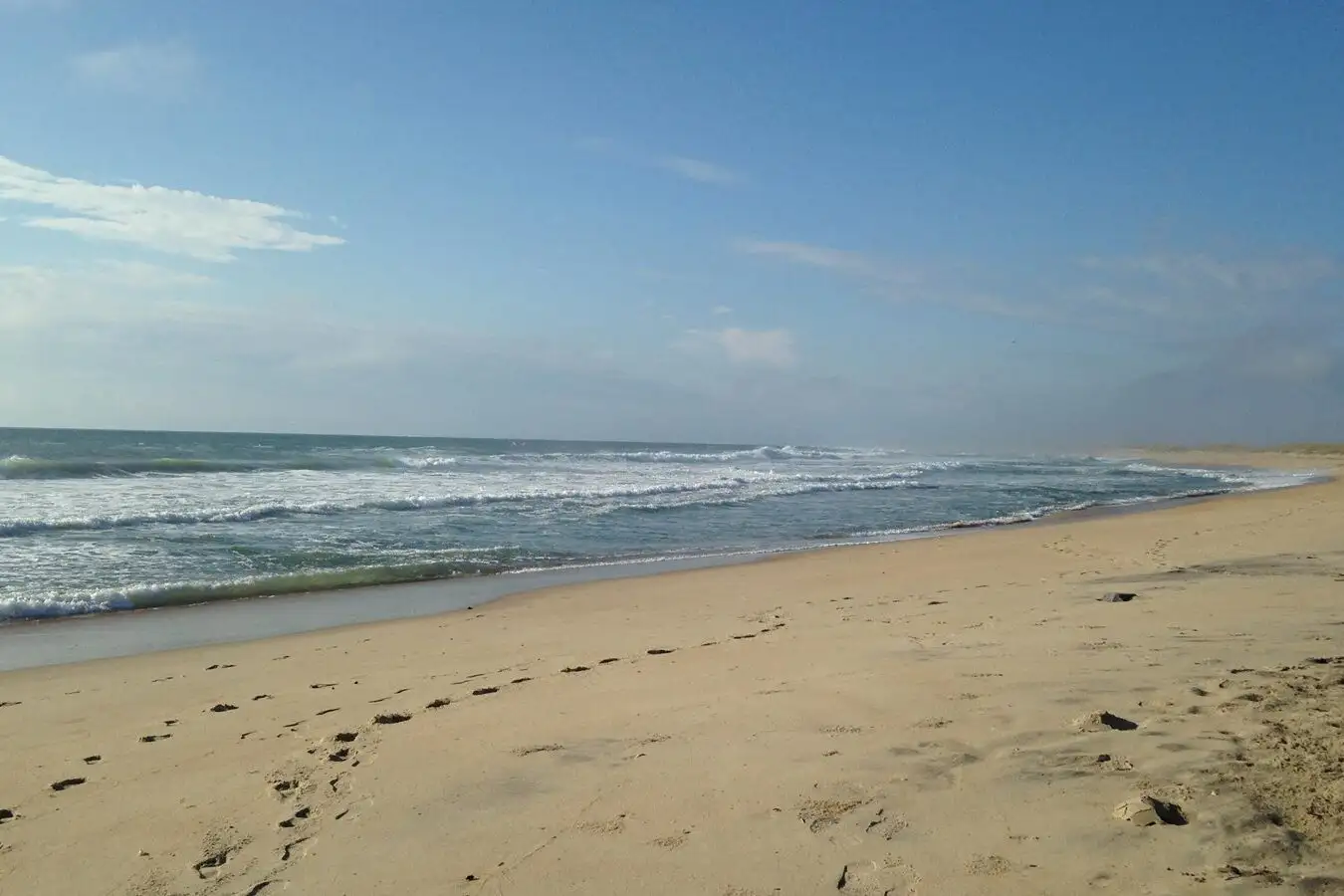 Empty Lighthouse Beach, Buxton, Outer Banks of North Carolina with waves coming on the white sand.