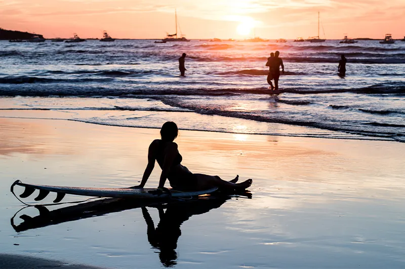 Silhouette of a person on a beach filled with surfers in Tamarindo, Costa Rica