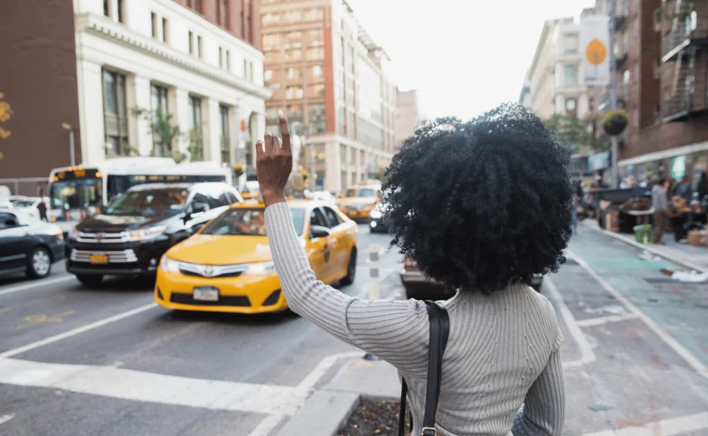 Woman hailing a taxi cab on a busy city street